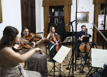 Fotografia. Koncert we wnętrzu Willi Decjusza. Muzycy grają na skrzypcach i wiolonczeli w Sali Balowej.